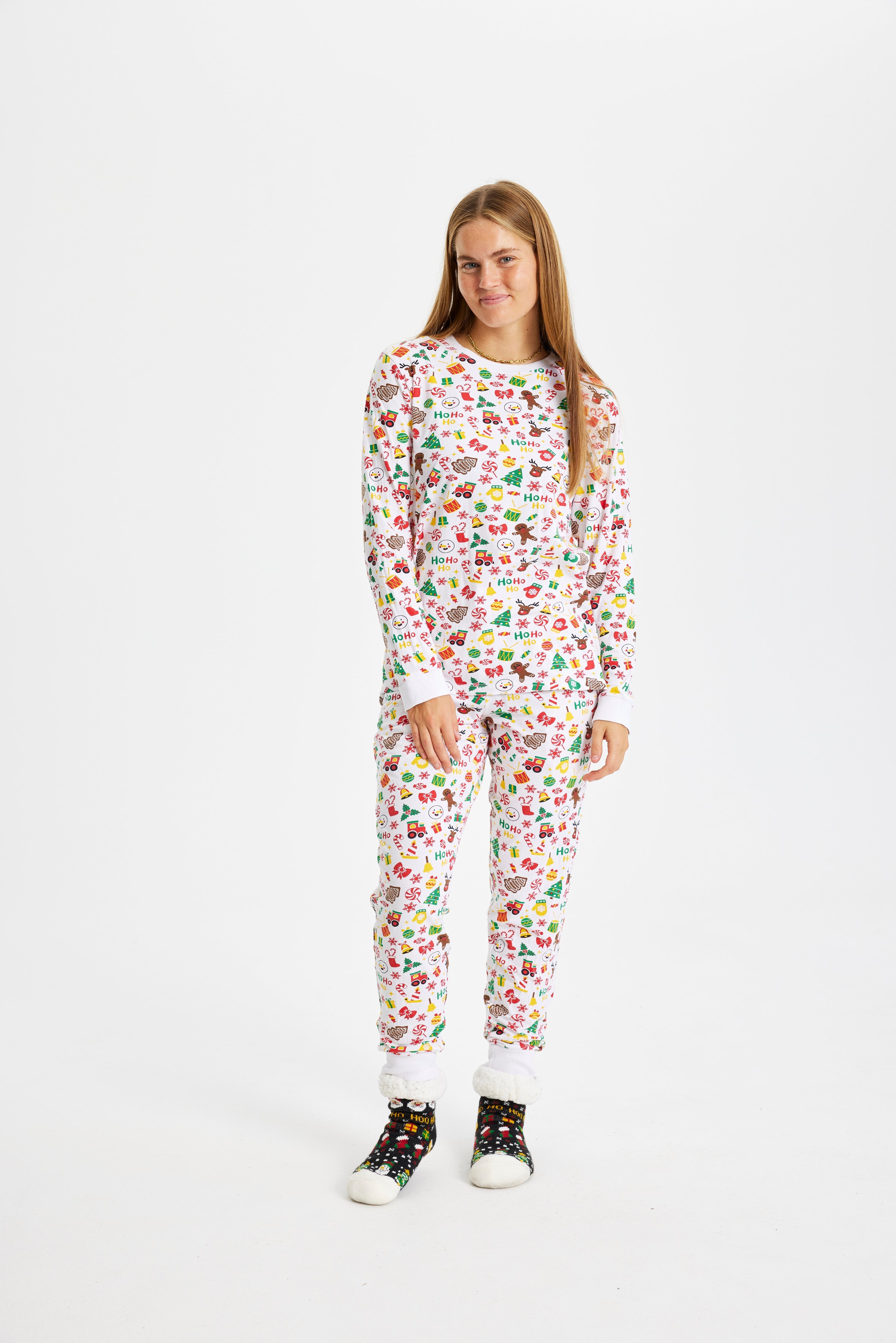 En smilende dame i en hvid, mønstret julepyjamas